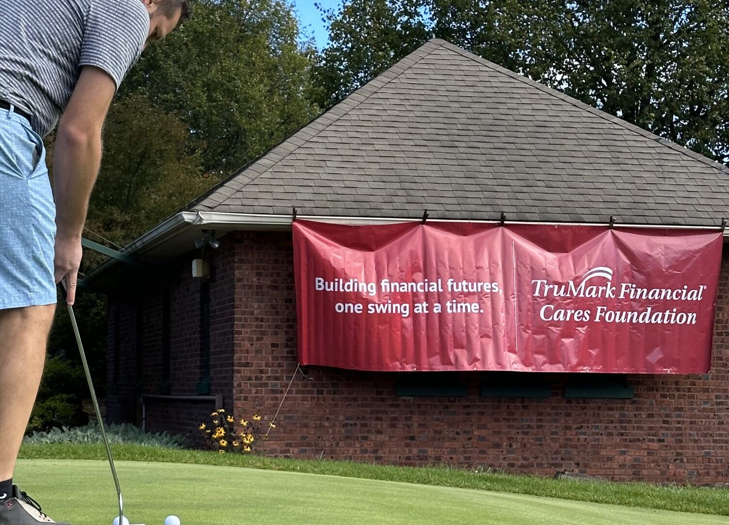 Man hitting a golf ball into a hole